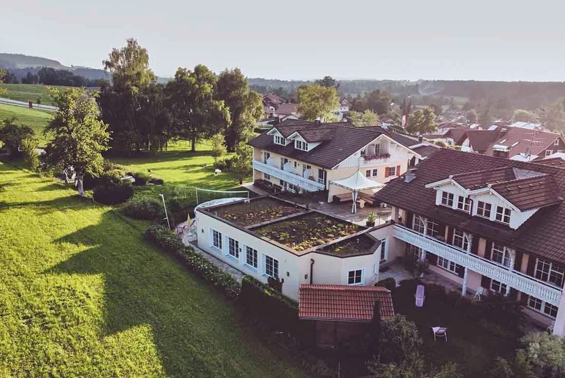 Blick von oben auf das Haus mit begrüntem Dachgarten und angrenzender Wiese