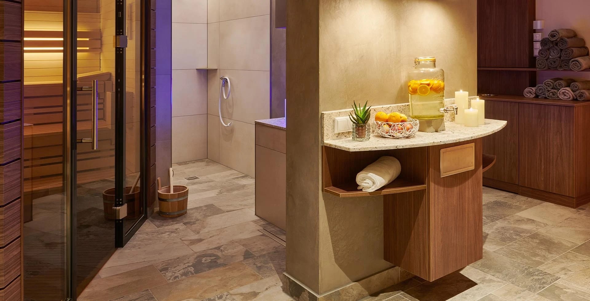 Spa-Bereich mit Sauna hinter Glastür, Dusche und Handtuchablage