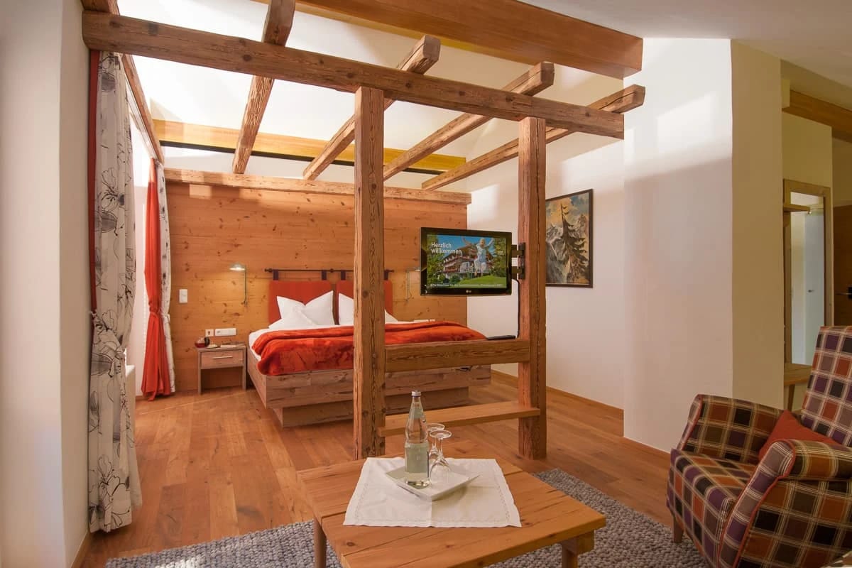 Studio mit freiliegendem Holzbalkengerüst um das Bett, Sitzecke und Holzwand