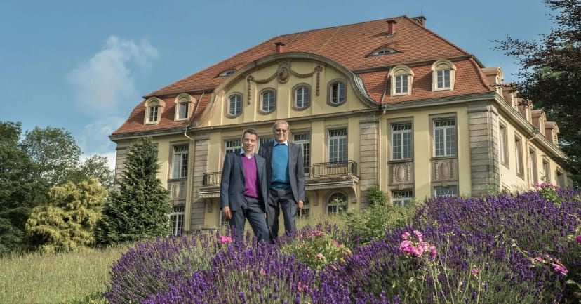 Historisches Klinikgebäude mit Mansarddach, davor ein blühendes Lavendelbeet