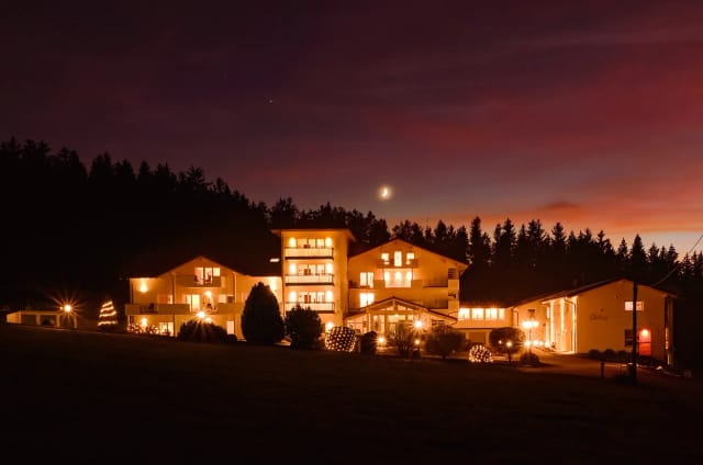 Das beleuchtete Hotelgebäude bei Nacht mit angestrahlter Fassade vor dem Abendhimmel