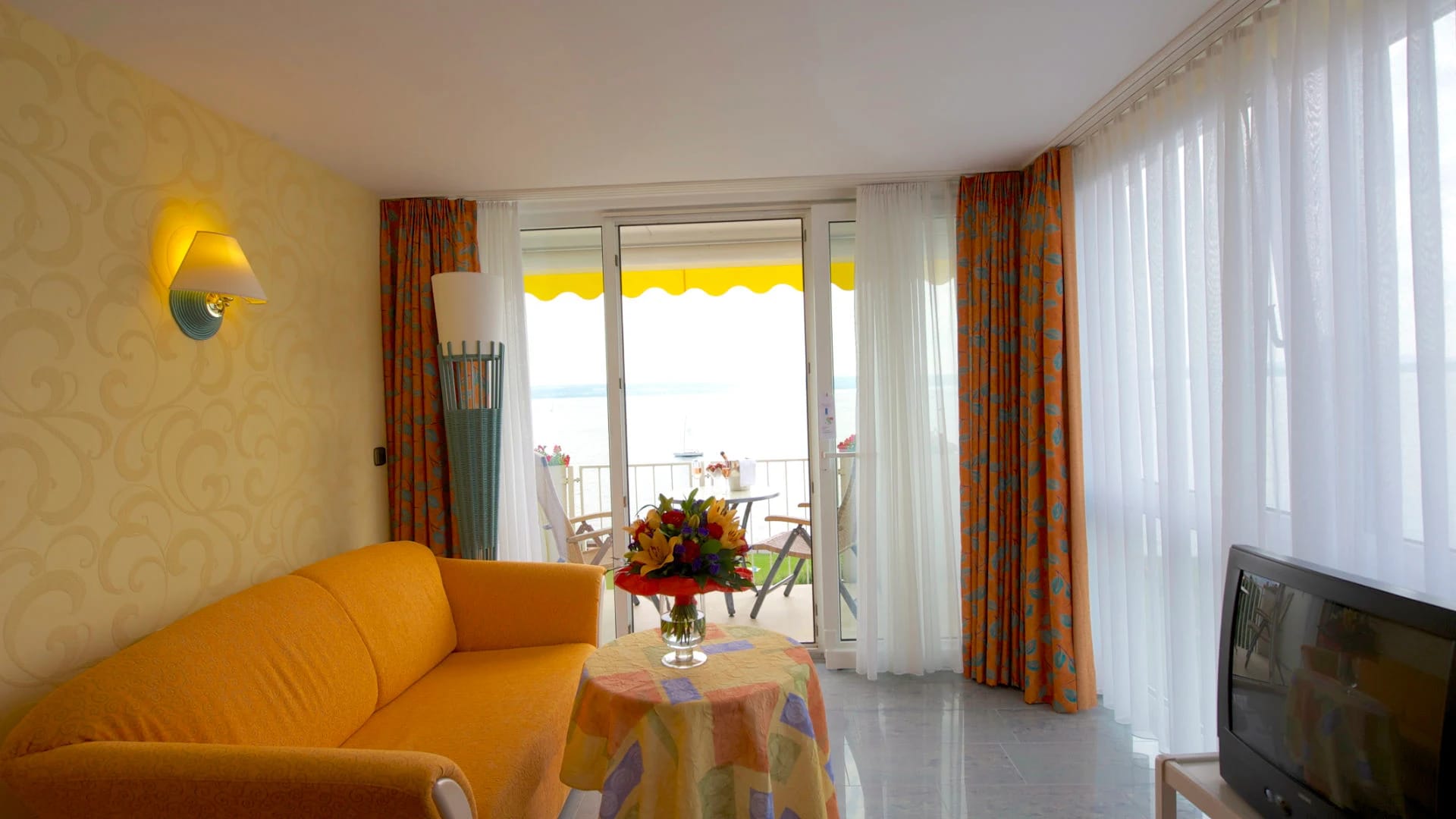 Wohnbereich mit Sofa, Tisch und geöffneter Balkontür mit Blick auf den Bodensee