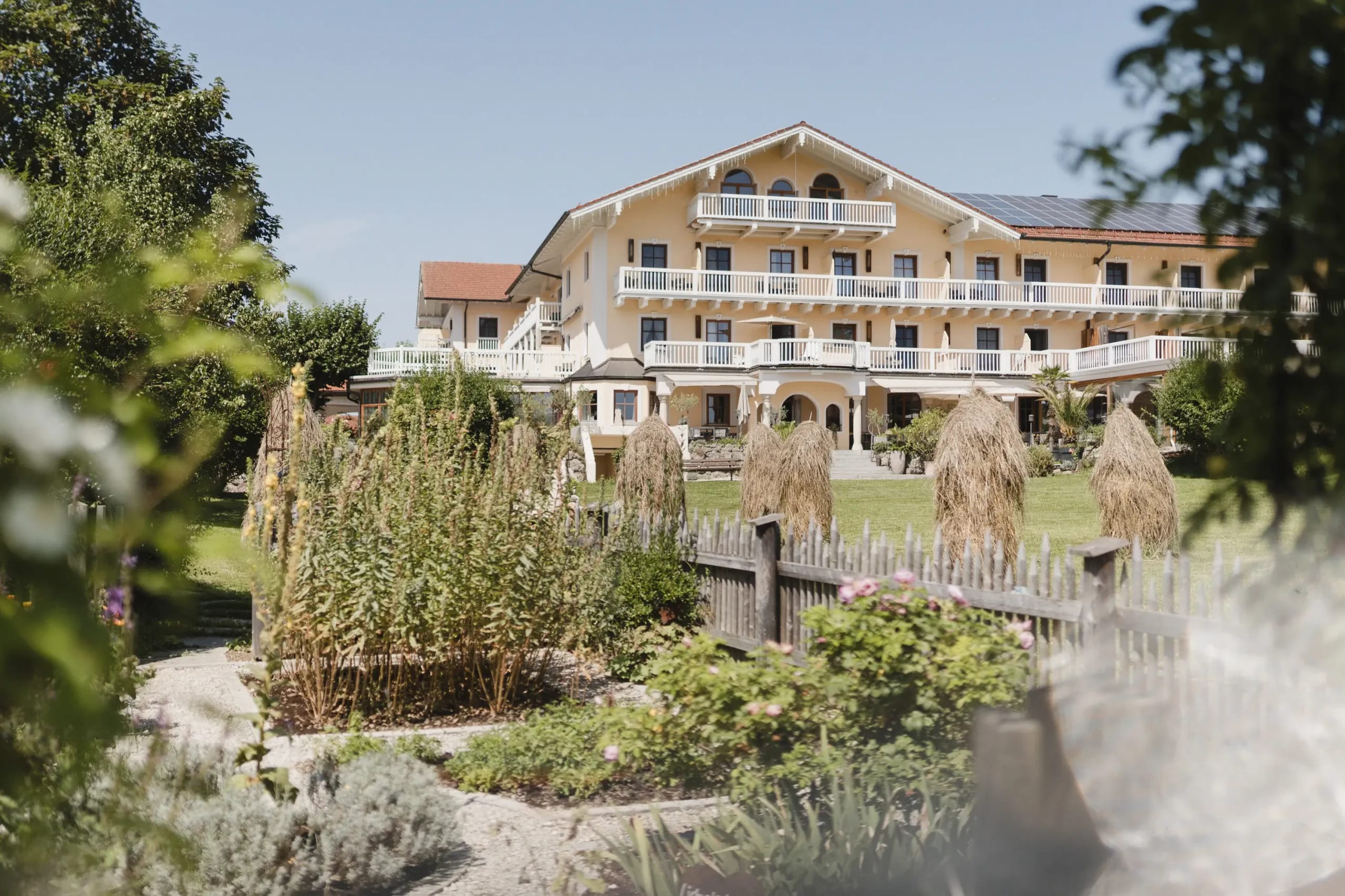 Gelbe Hotelfassade mit Balkonen hinter dem Gartenbereich