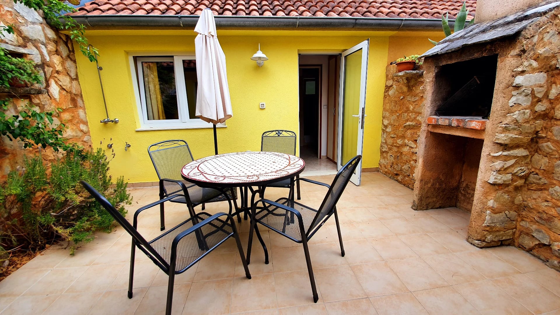 Terrasse eines Ferienhauses mit Sitzgruppe und Steingrill