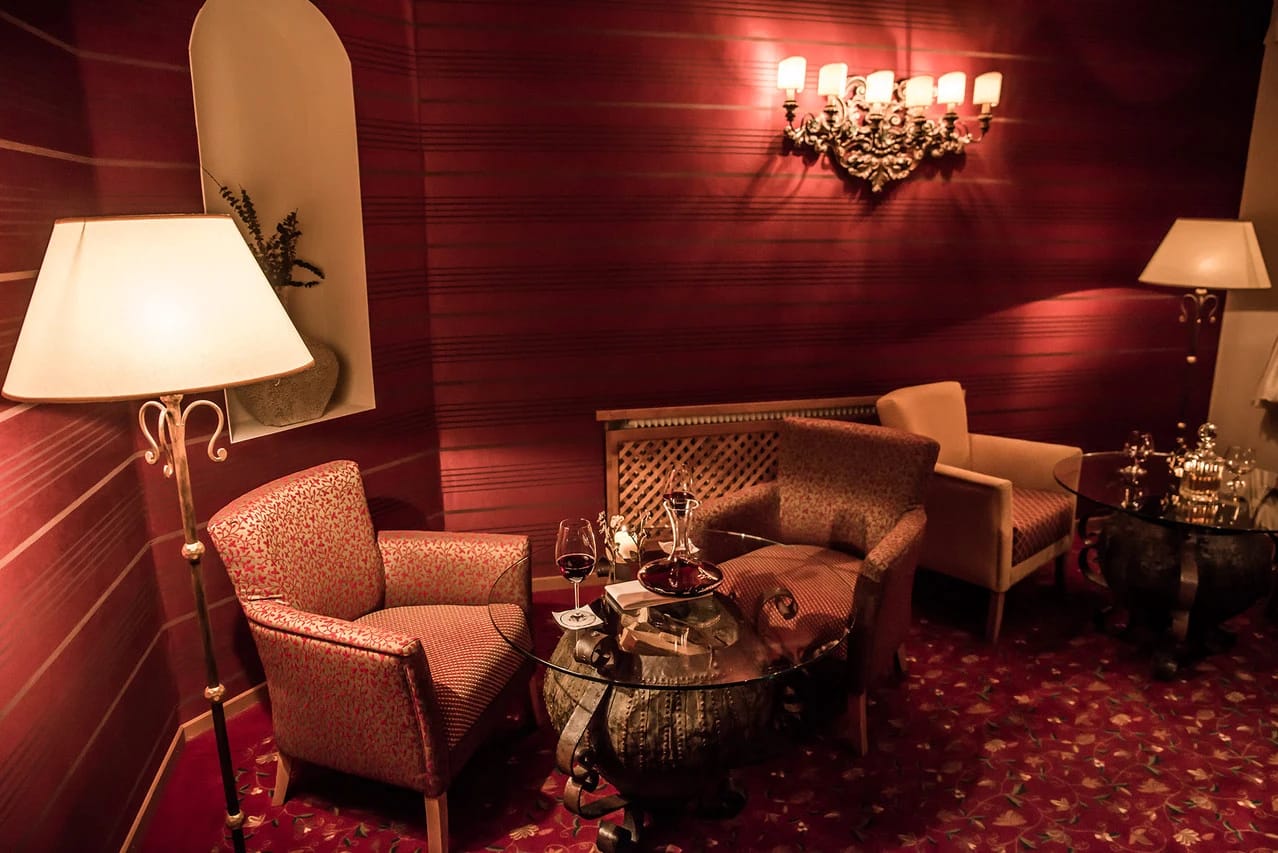 Gemütliche Lounge mit Polstersesseln und Stehlampen in warmen Rottönen