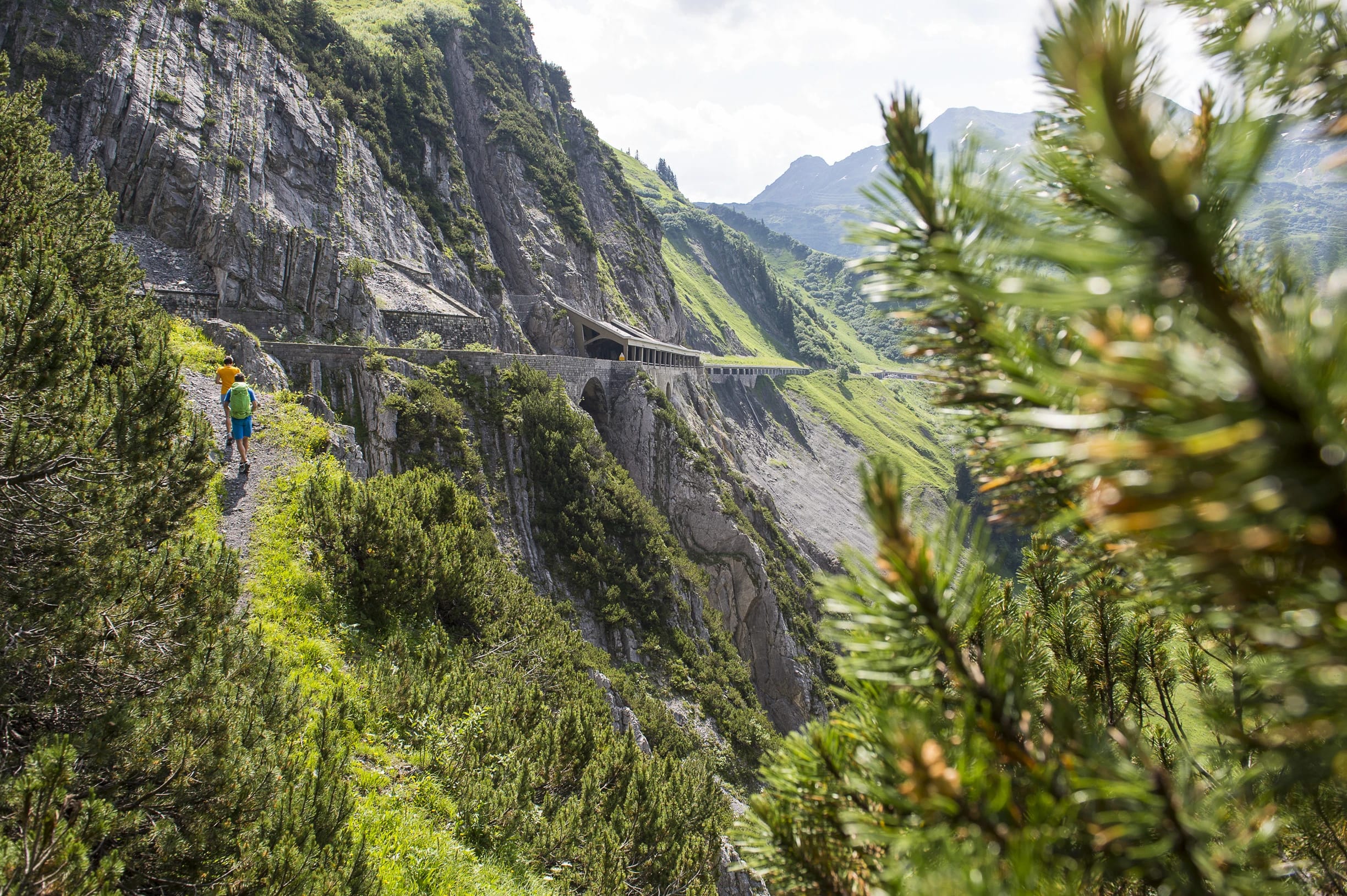 Wanderweg an einer Felswand mit Blick ins Bergtal