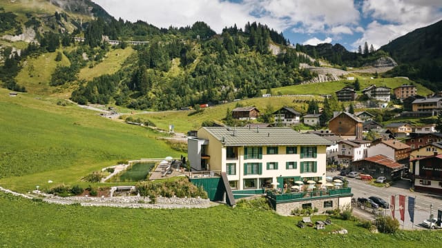 Außenansicht des Hotels Arlberg Stuben im Bergdorf mit Wiese und Bergpanorama