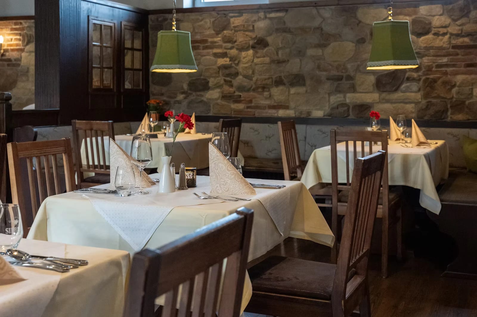 Restaurant mit Natursteinwand und eingedeckten Tischen