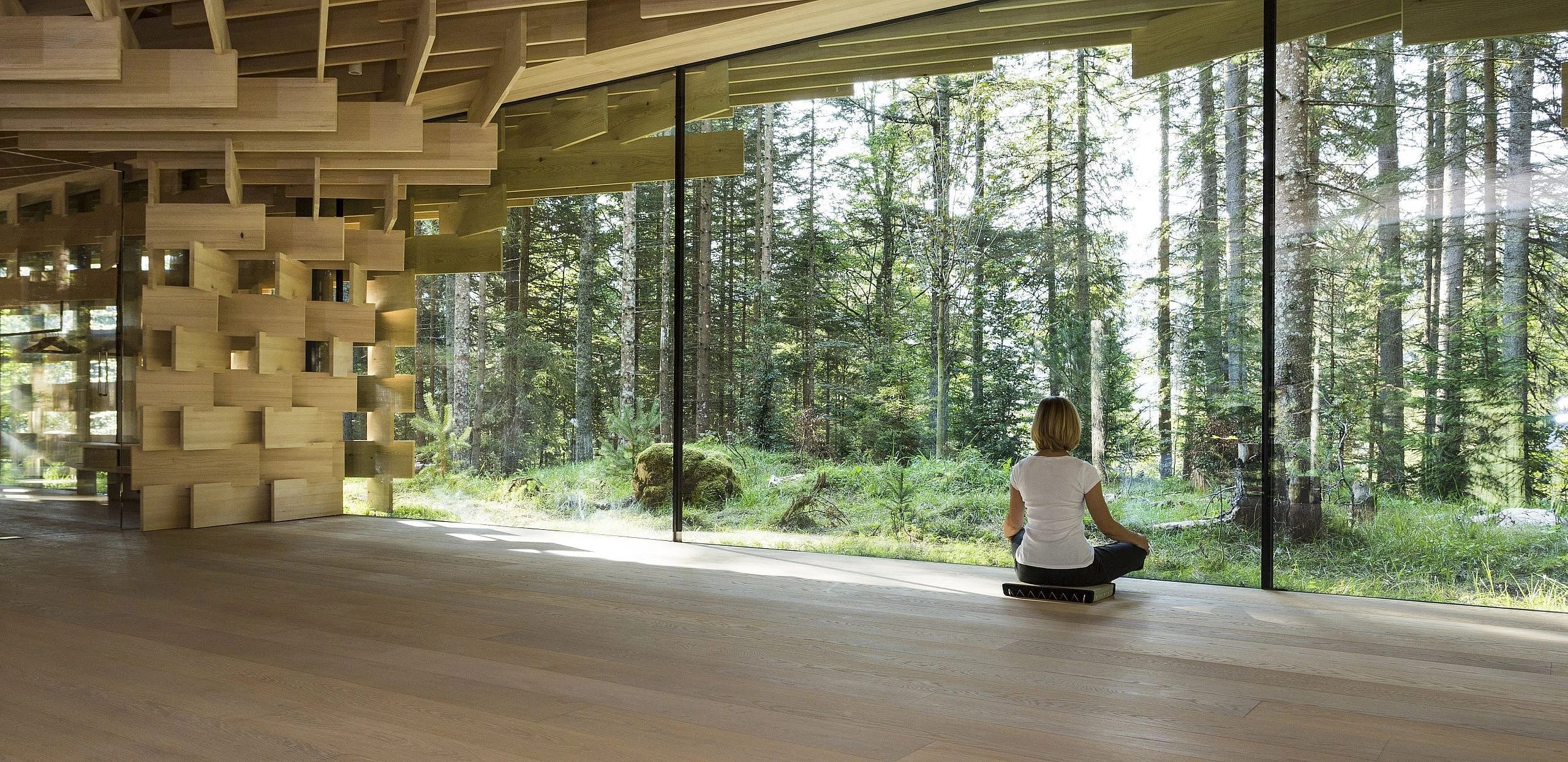 Holzverkleideter Meditationsraum mit raumhoher Verglasung zum umgebenden Wald