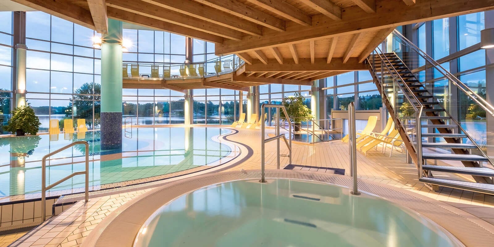 Hallenbad mit Schwimmbecken, Whirlpool und offener Holzdecke