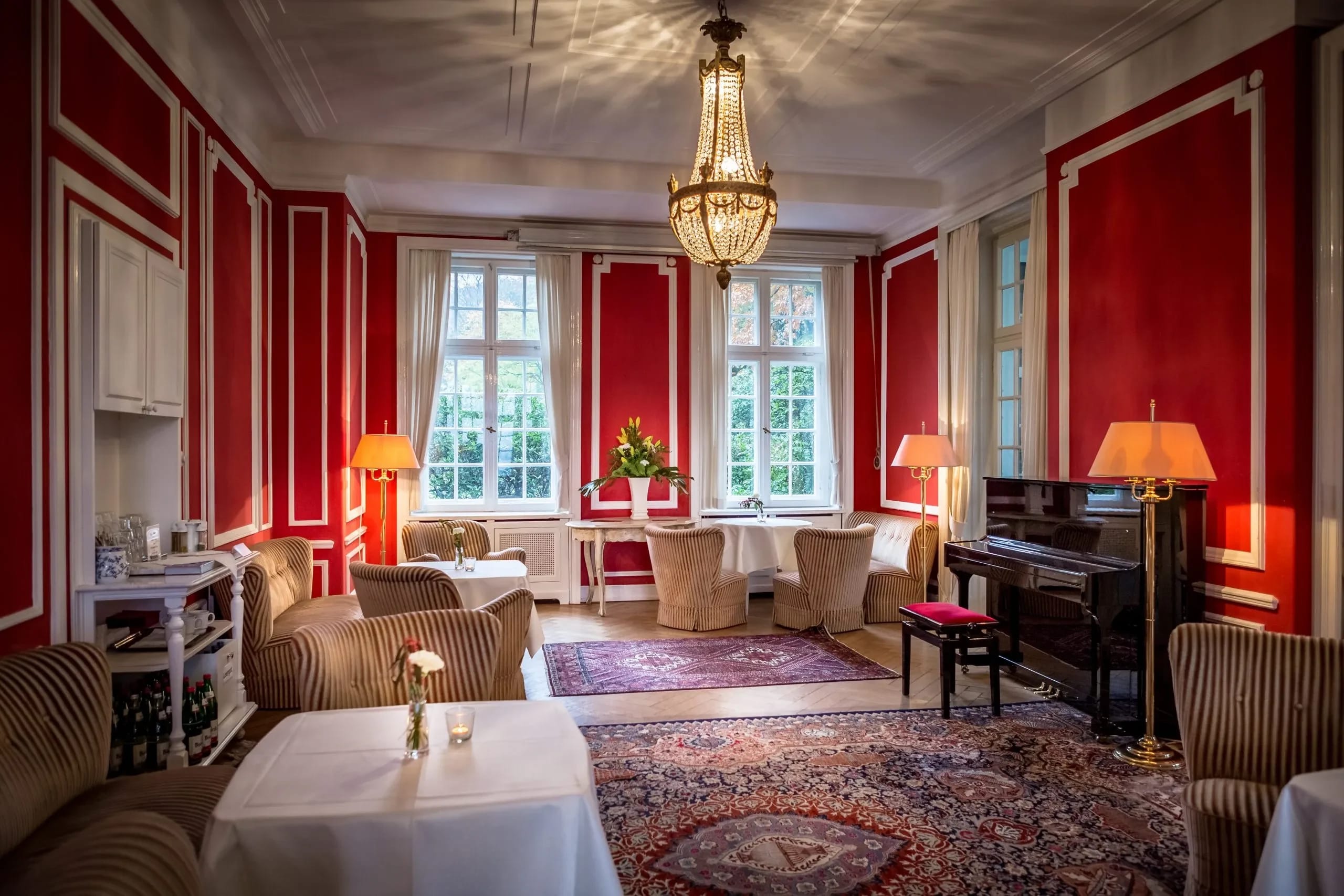 Roter Salon mit Sesseln, Flügel und Kronleuchter