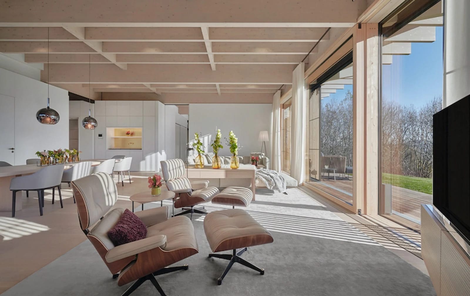 Heller Wohnraum mit Holzdecke, Sesseln und raumhoher Verglasung zur Terrasse