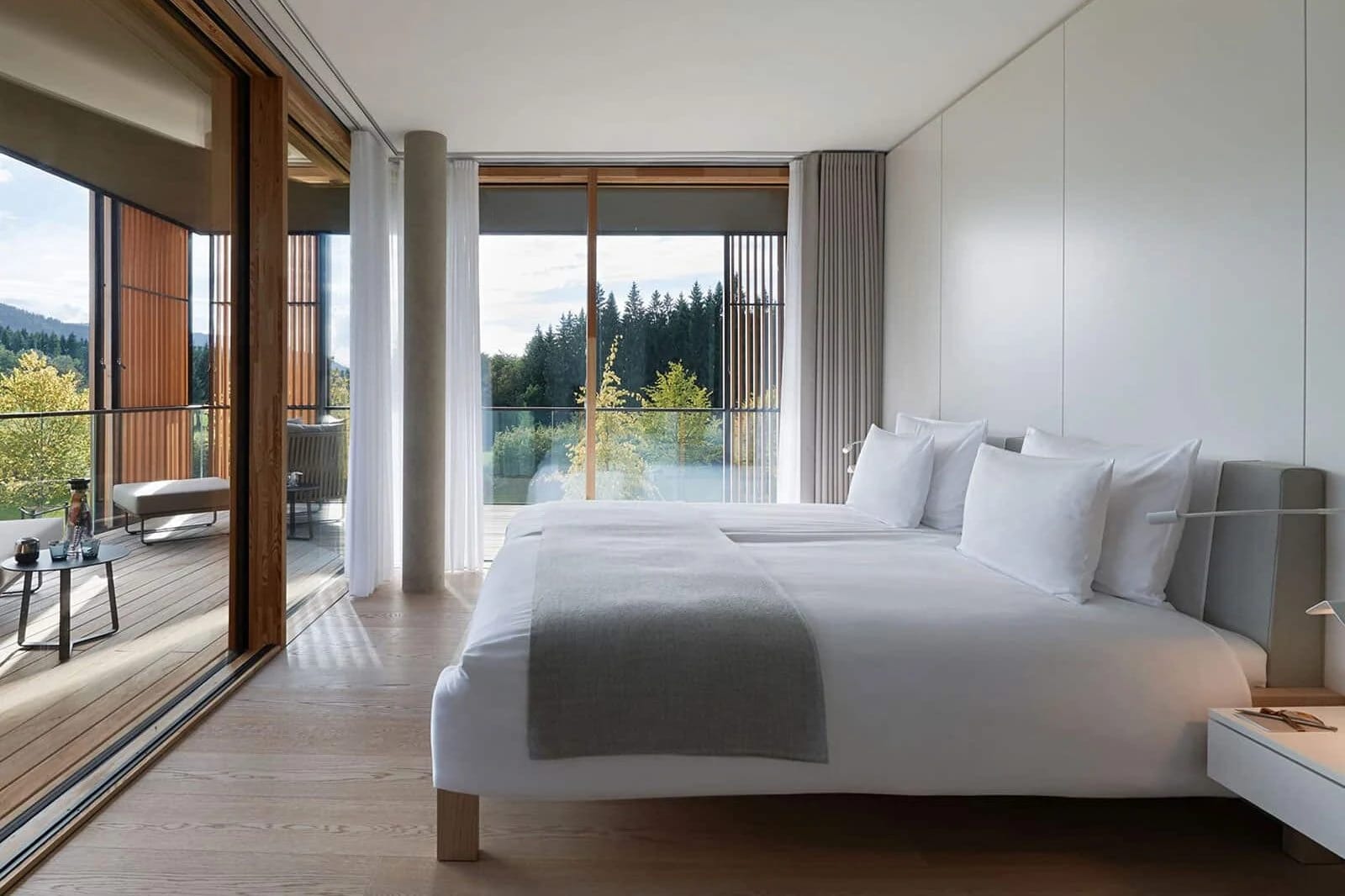 Schlafzimmer mit Doppelbett, angrenzendem Balkon und Blick auf Wald und Wasser
