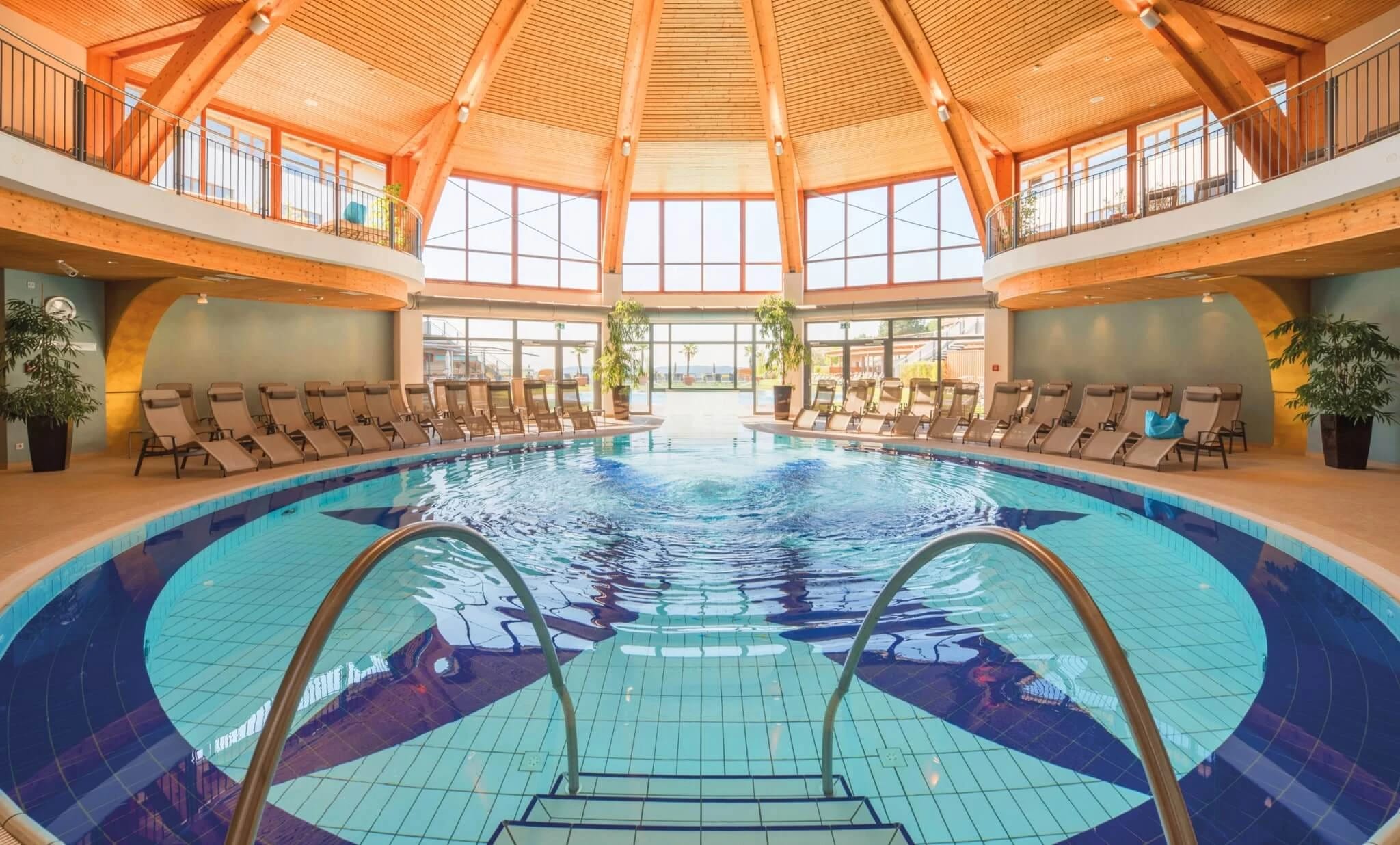 Hallenbad unter einer Holzkuppel mit Liegestühlen
