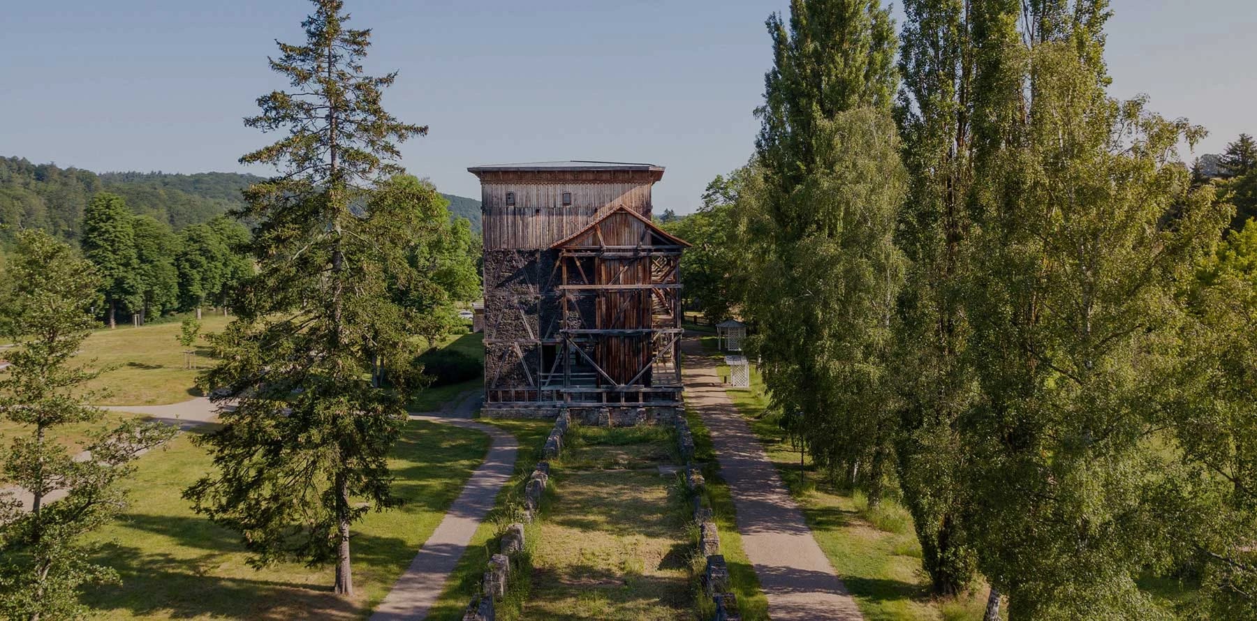 Hölzernes Gradierwerk in einem Park mit Bäumen und Wegen