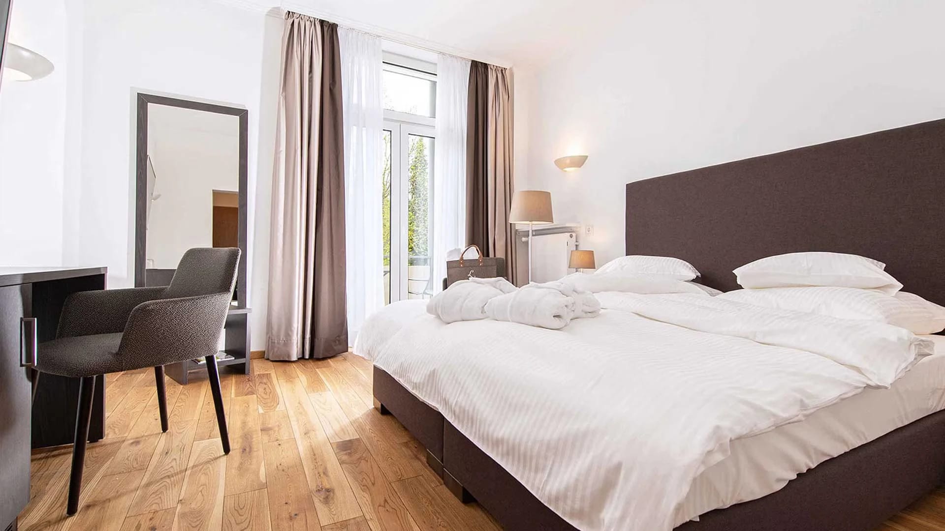 Helles Zimmer mit Doppelbett, Holzdielenboden und Balkontür
