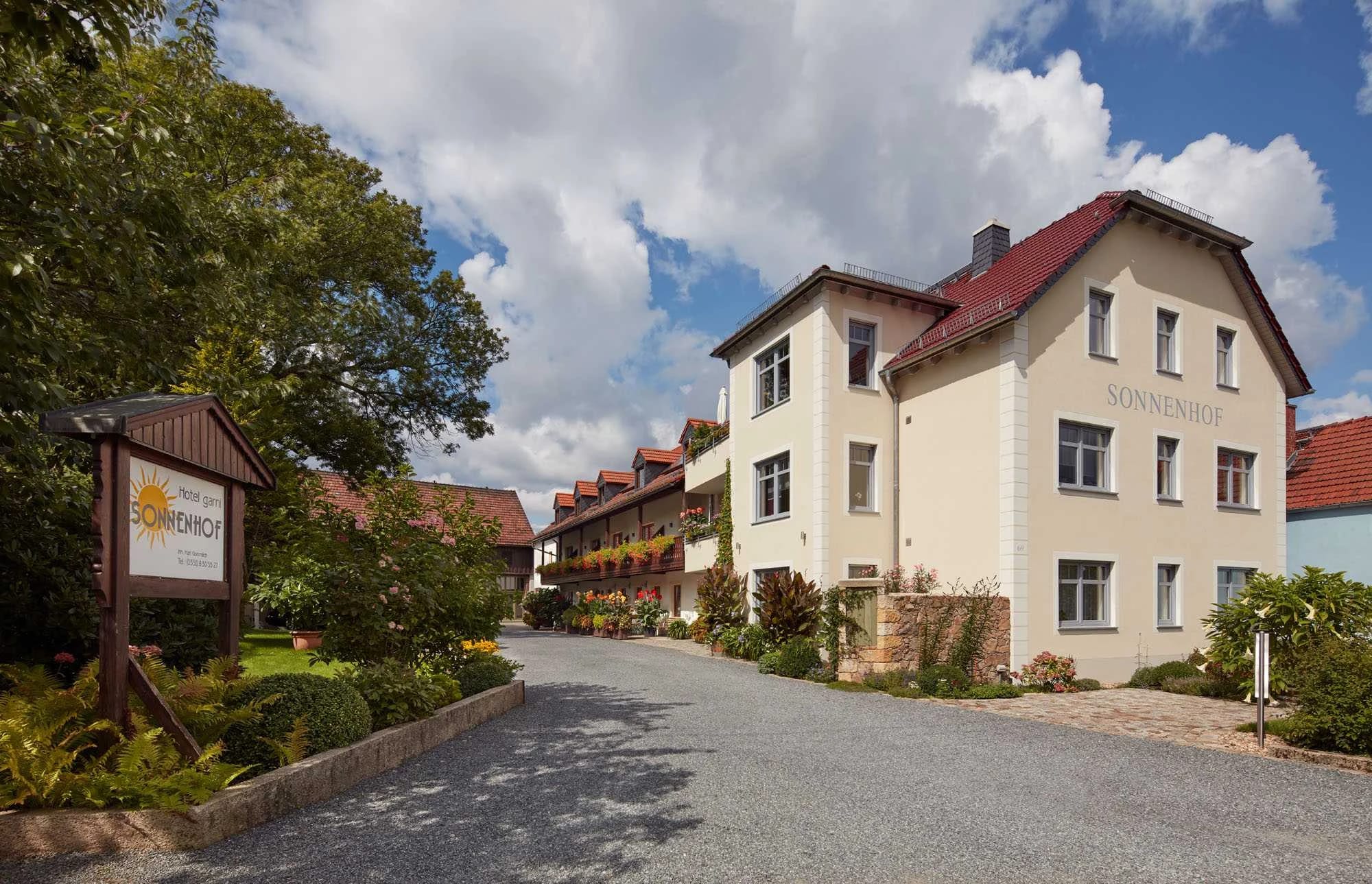 Außenansicht des Sonnenhofs mit Eingangsschild und Blumenbeeten