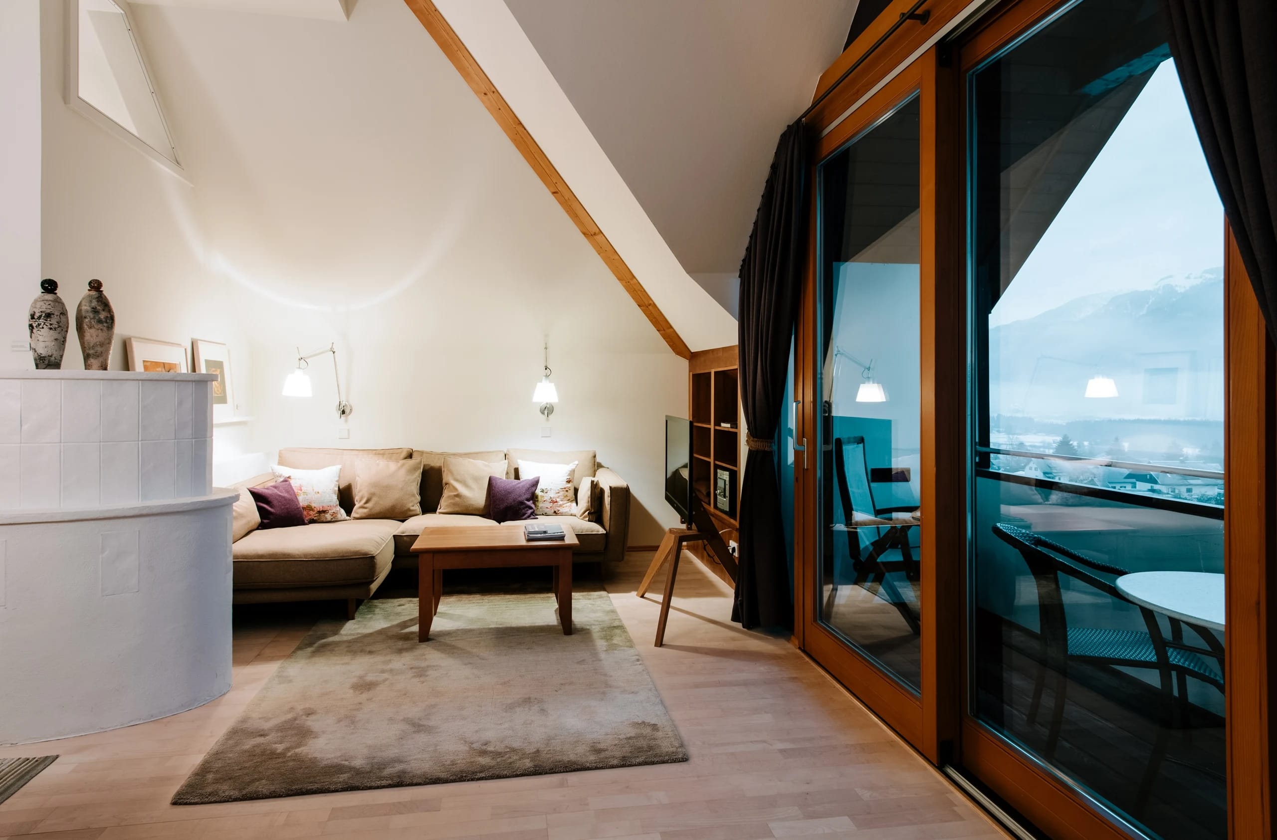 Loftzimmer mit Sitzecke unter hohem Dach und Glastür zum Balkon