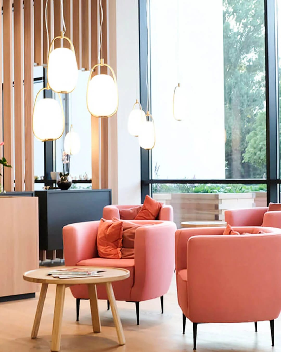 Lounge-Bereich mit rosafarbenen Sesseln und Hängeleuchten
