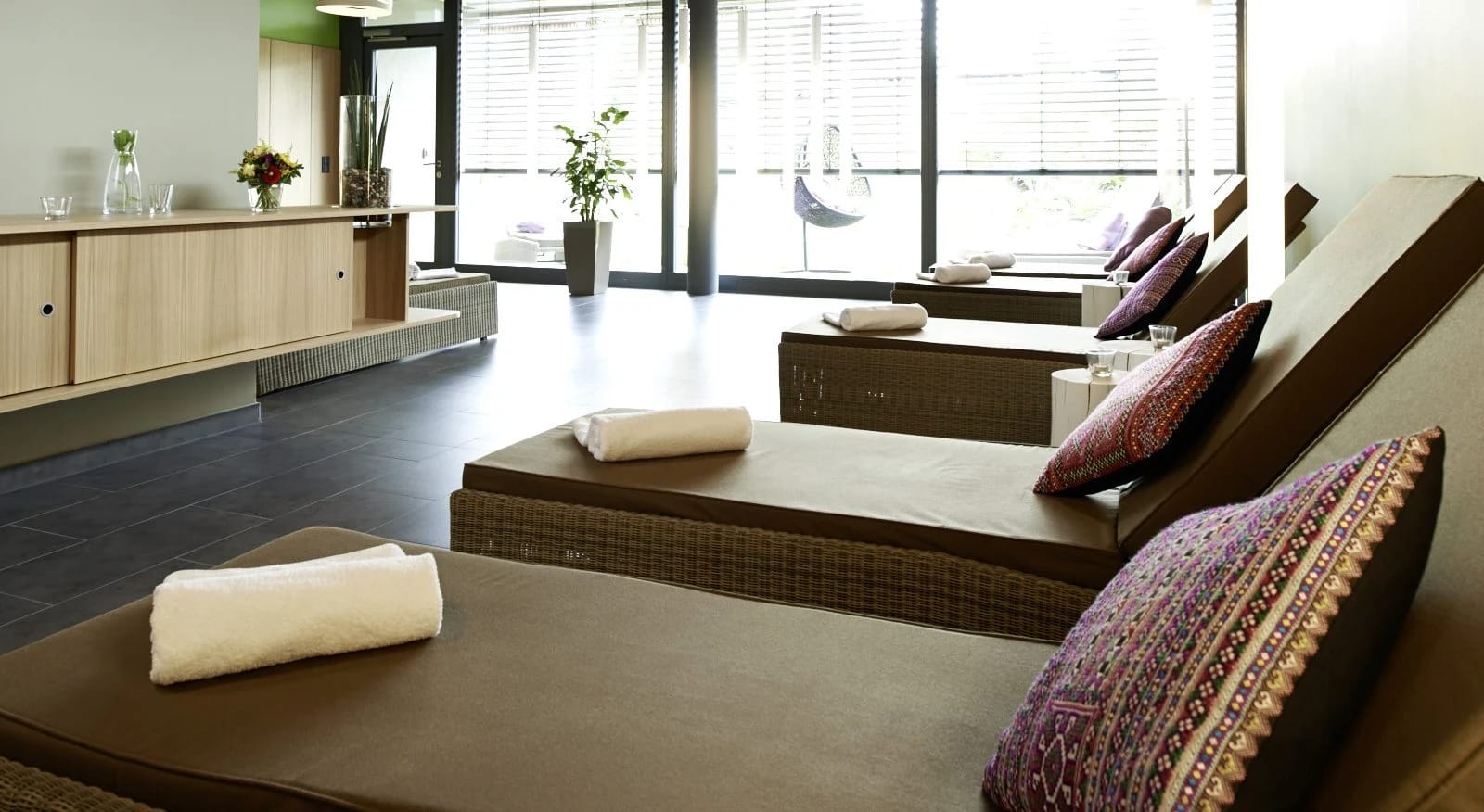Wellness-Ruheraum mit gepolsterten Liegen und großen Fenstern