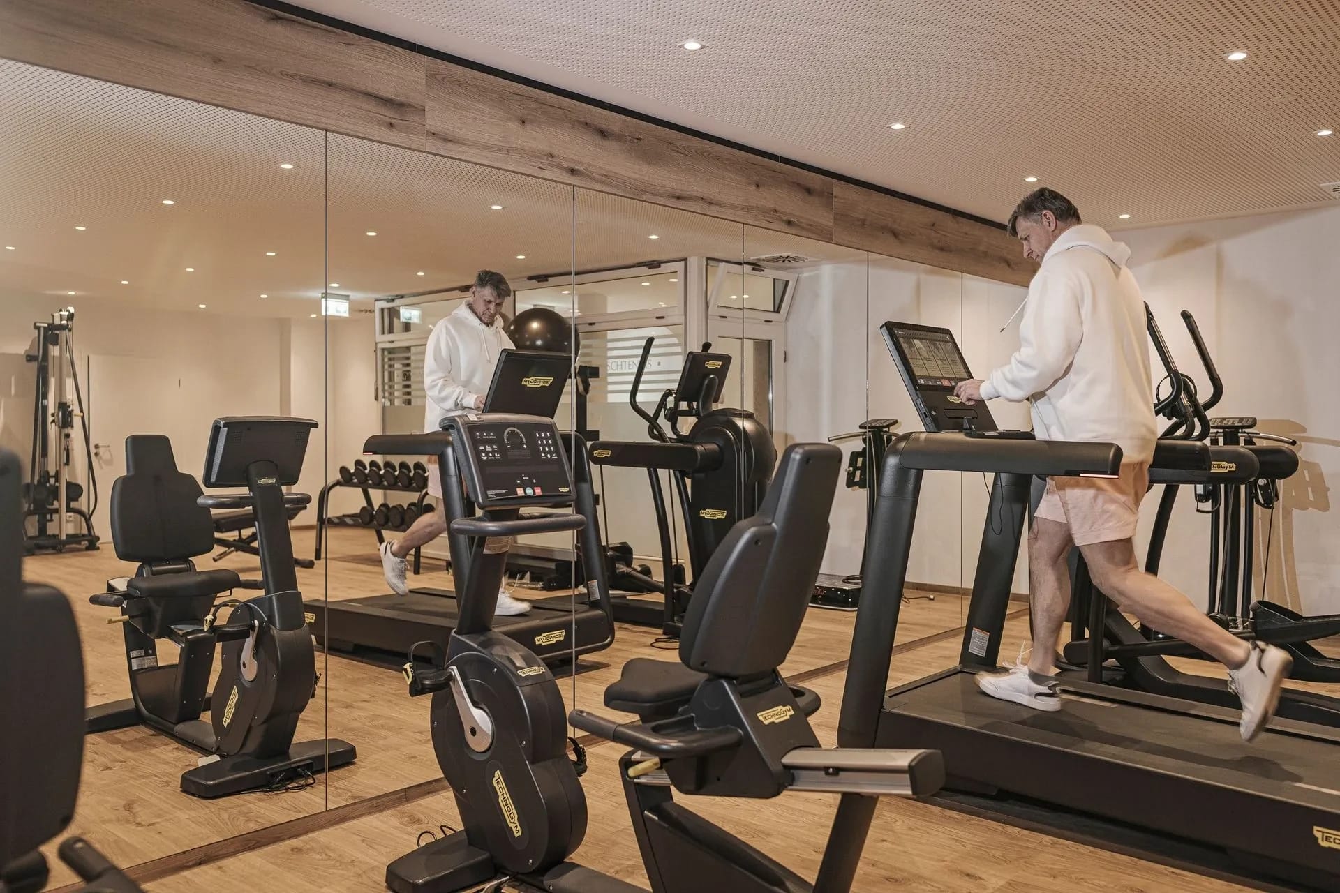 Fitnessraum mit Laufbändern, Ergometern und verspiegelter Wand