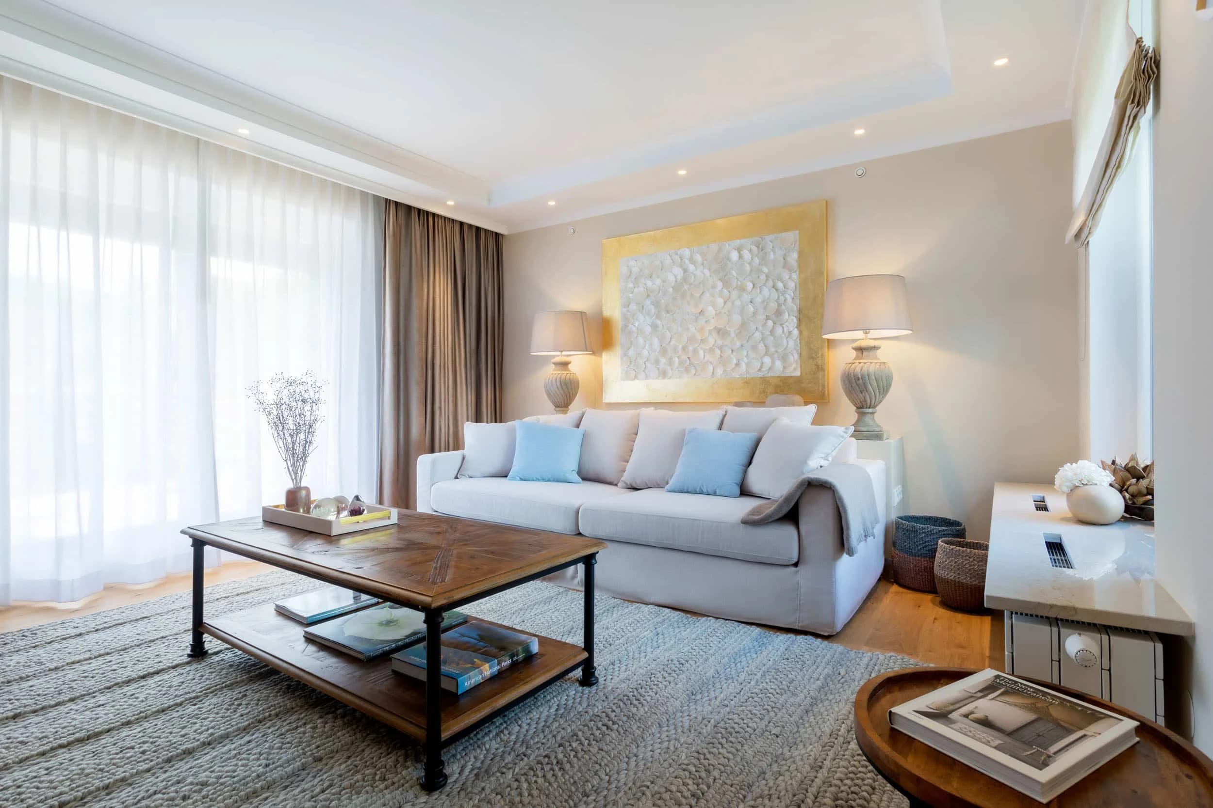 Wohnzimmer einer Suite mit heller Couch, Couchtisch und Wandbild