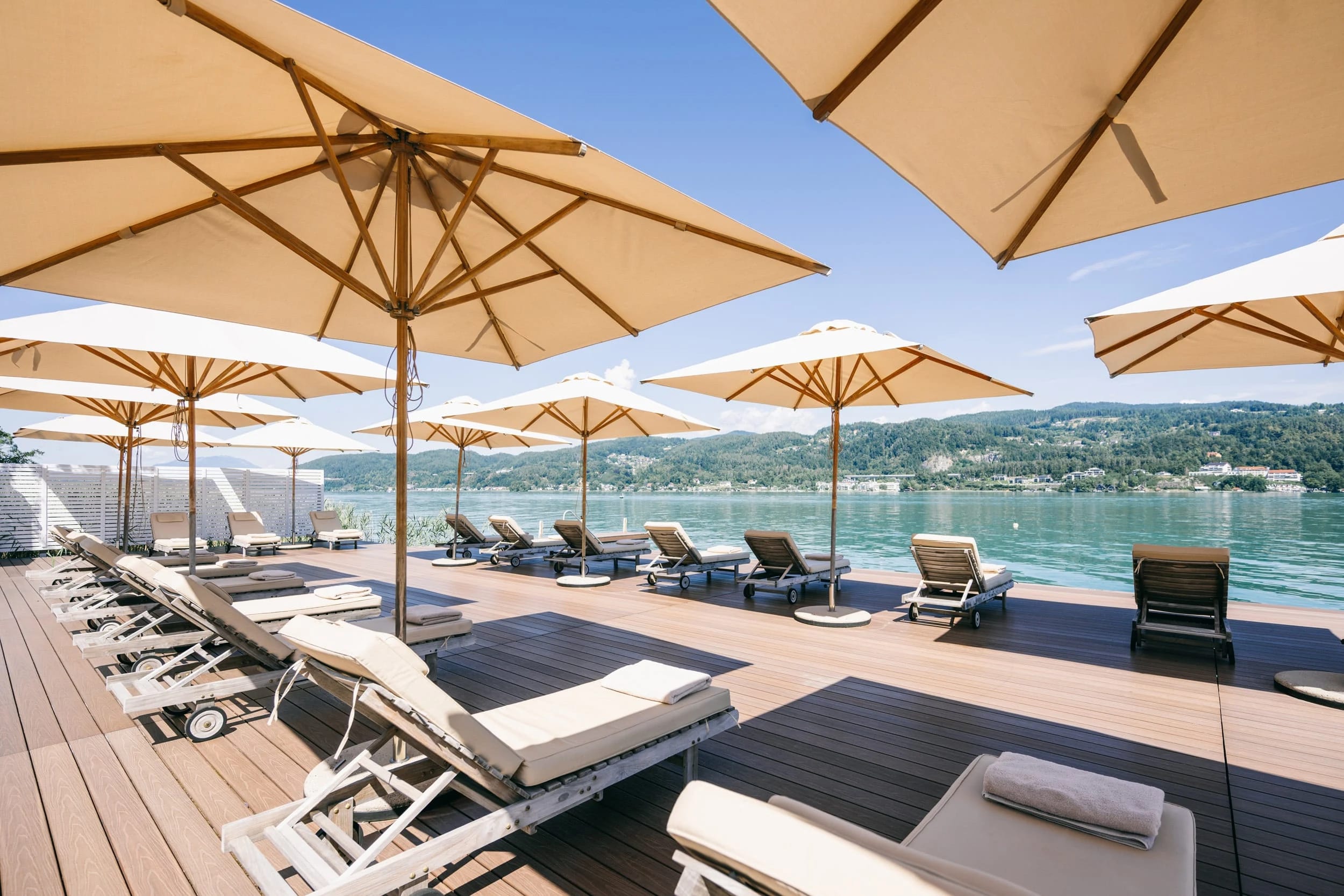 Sonnenterrasse am See mit Liegen und Sonnenschirmen