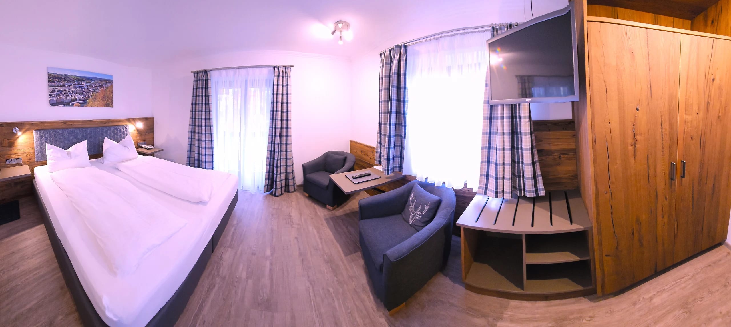 Doppelzimmer mit breitem Bett, Kleiderschrank, Sesselecke und Balkontür