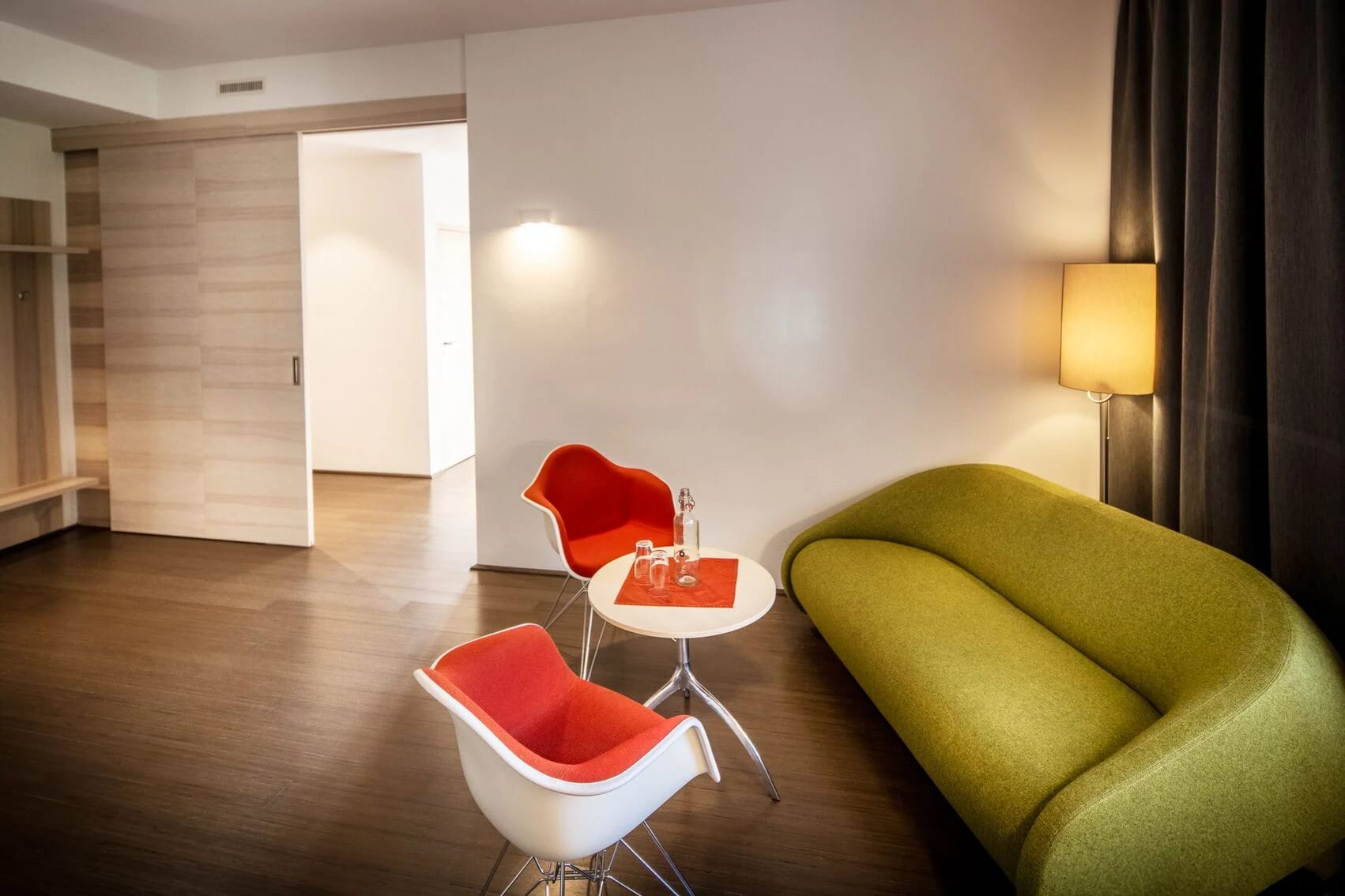 Aufenthaltsraum mit roten Sesseln, grünem Sofa und Stehlampe