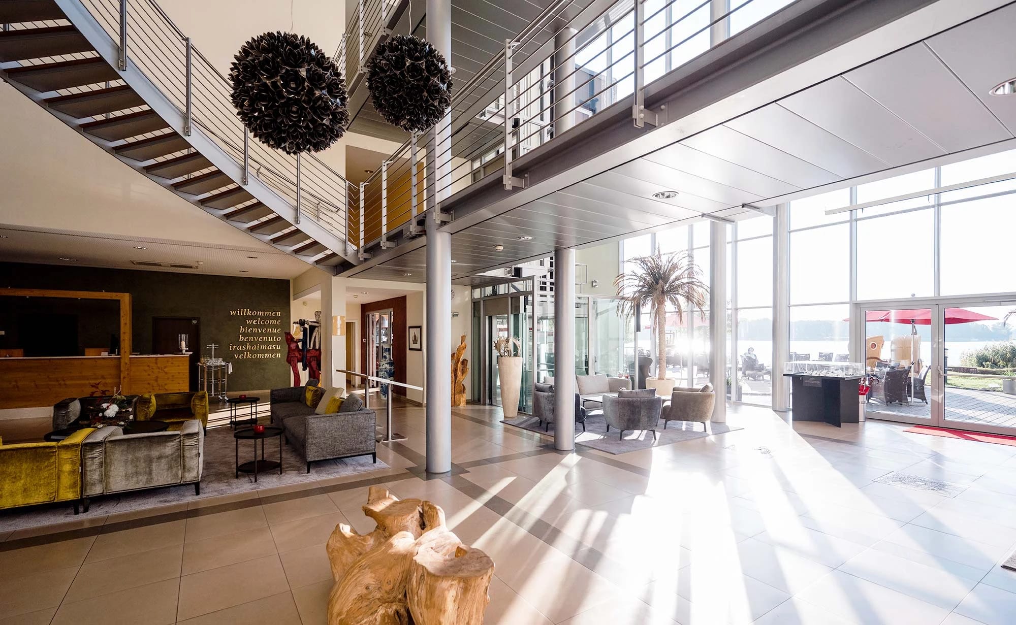 Hotellobby mit Rezeption, Sitzgruppen, offener Galerie und großer Fensterfront