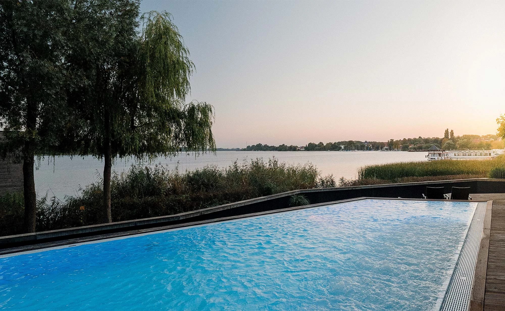 Sole-Außenpool mit Blick über den Ruppiner See in der Abenddämmerung, am Ufer eine Trauerweide