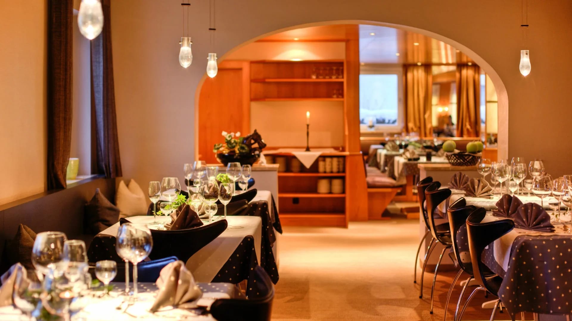 Restaurant mit Rundbogen, eingedeckten Tischen und warmem Licht