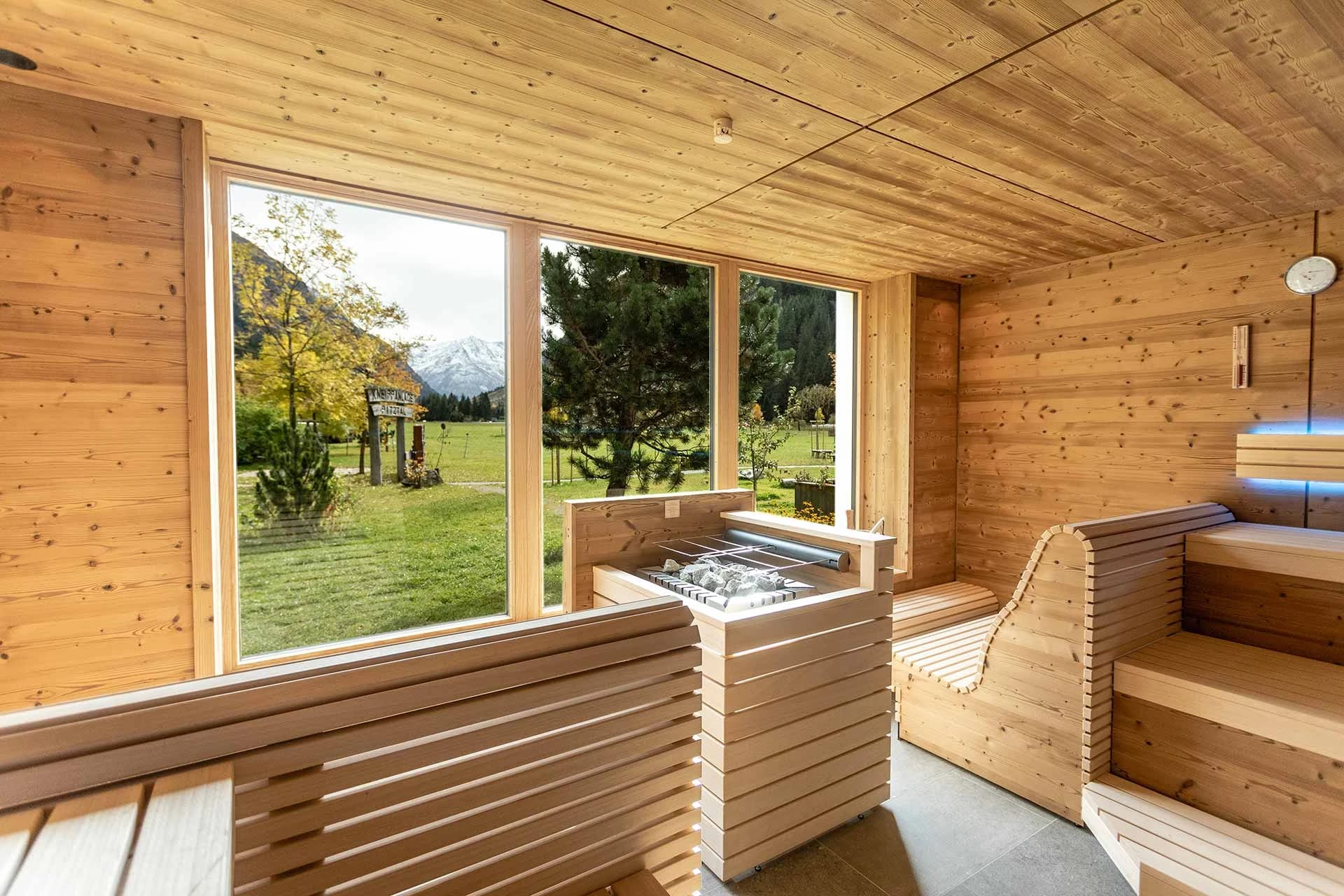 Finnische Holzsauna mit großem Panoramafenster und Blick in die grüne Natur