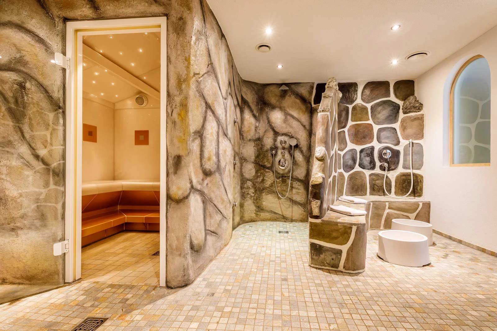 Wellnessbereich in Natursteinoptik mit Erlebnisdusche und Zugang zur Sauna