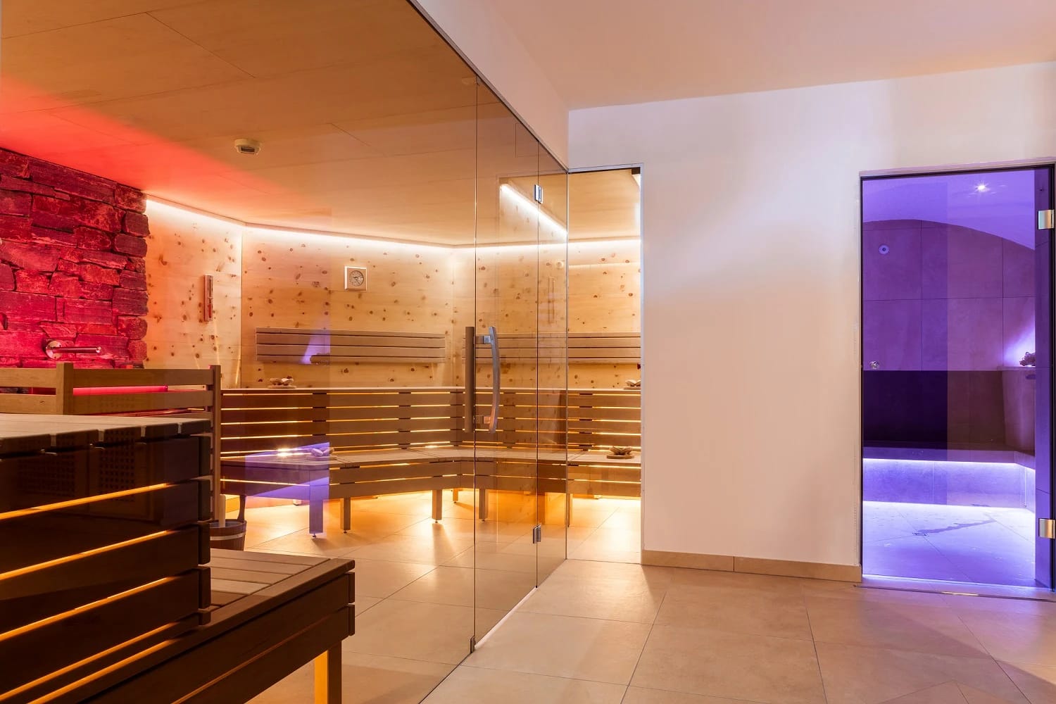 Saunalandschaft mit Finnischer Sauna und Dampfbad hinter Glas