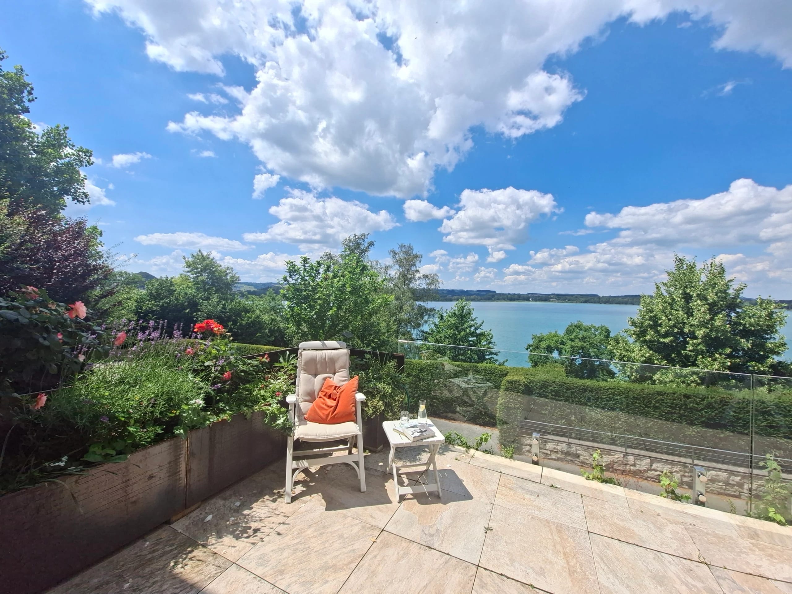 Terrasse mit Liegestuhl und Blick auf einen See