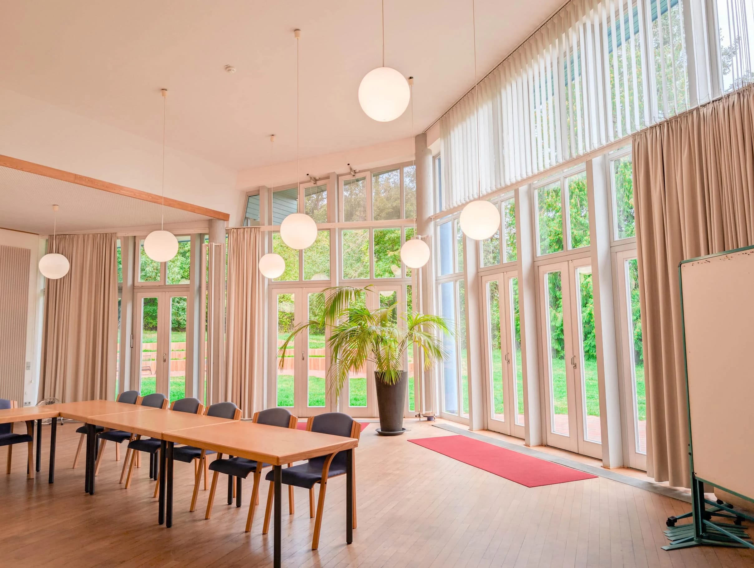 Lichtdurchfluteter Seminarraum mit hoher Fensterfront und langem Tisch