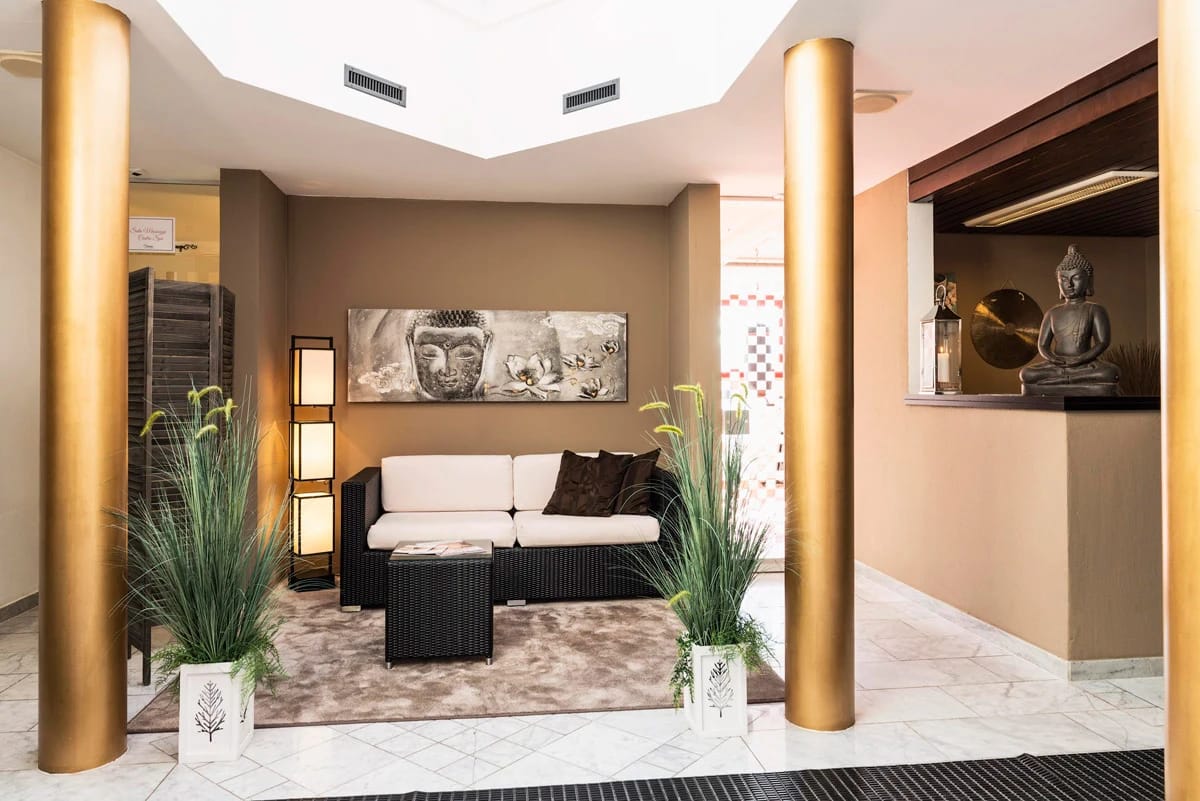 Empfangsbereich des Spa mit Sofa, goldenen Säulen und Buddha-Figur