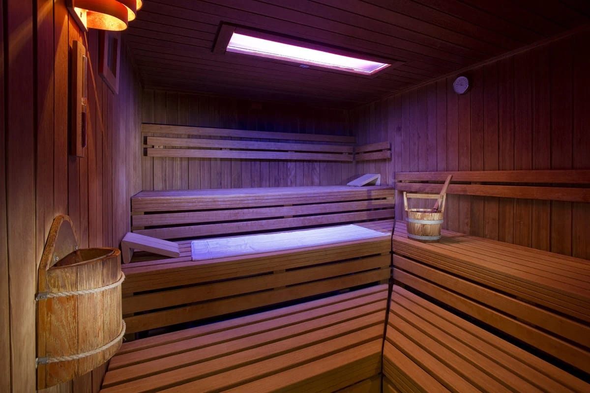 Finnische Sauna mit mehrstufigen Holzbänken, Holzkübel und farbigem Deckenlicht