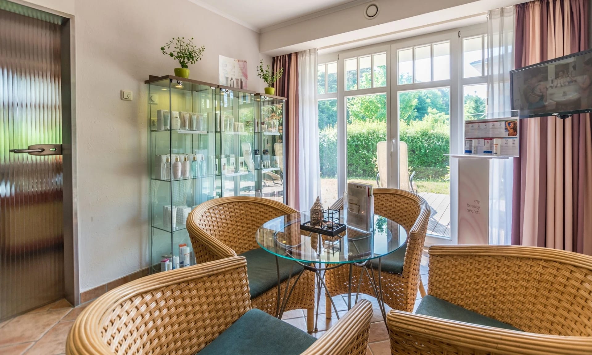 Sitzecke im Spa mit Korbsesseln und Glastisch am Fenster