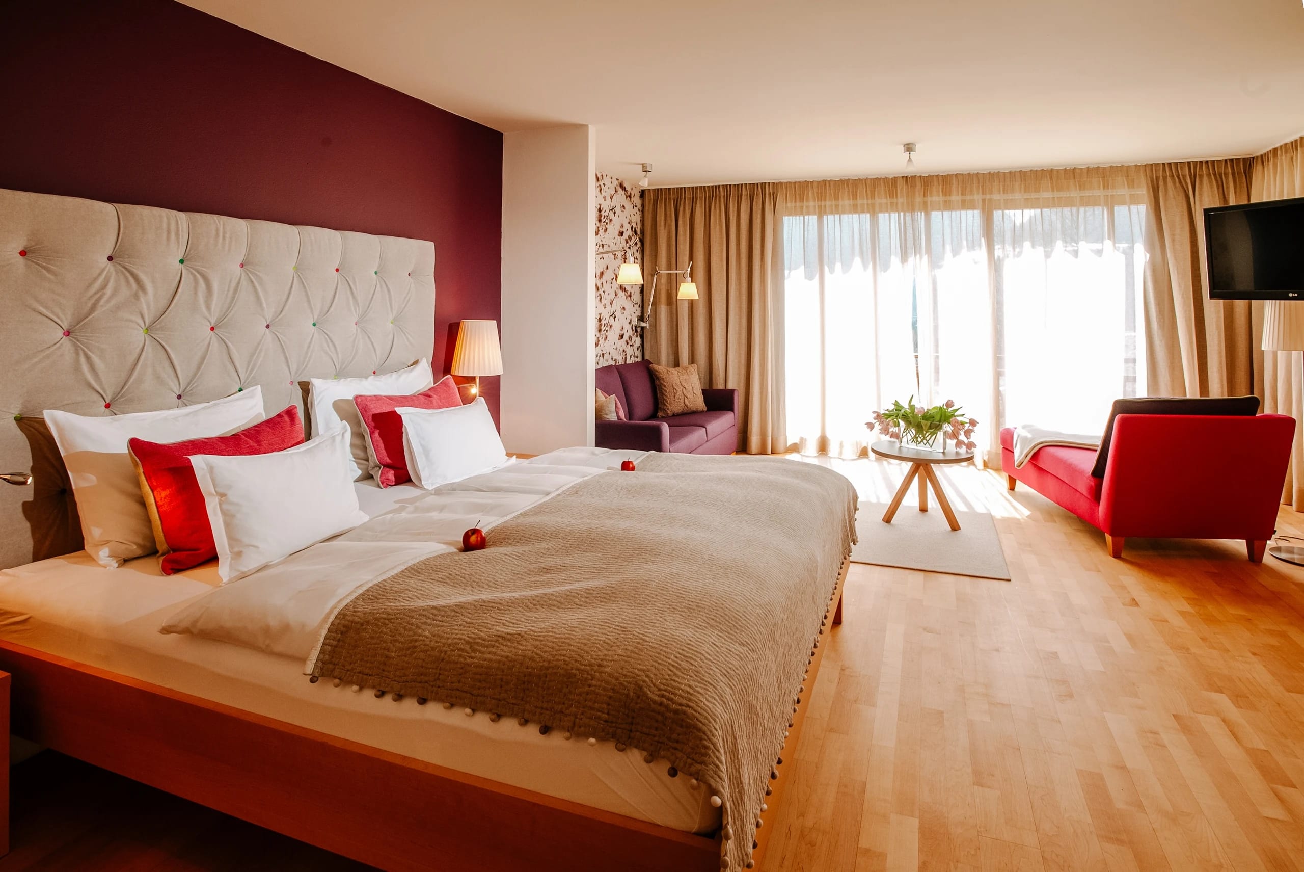 Helle Zimmer-Sitzecke mit Sofa unter Dachschräge und großer Fensterfront zum Balkon