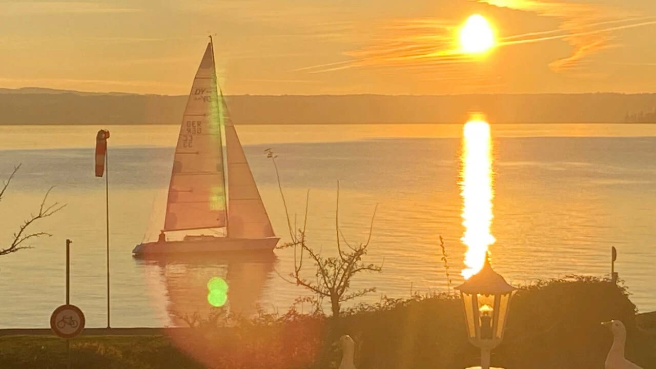 Sonnenuntergang über dem Bodensee mit Segelboot