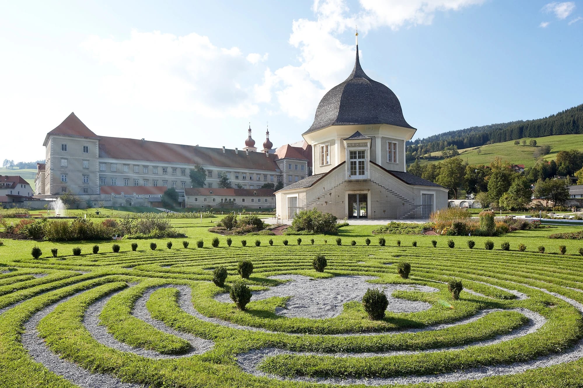 Gartenpavillon mit Buchsbaum-Labyrinth auf der Wiese, im Hintergrund das Stiftsgebäude