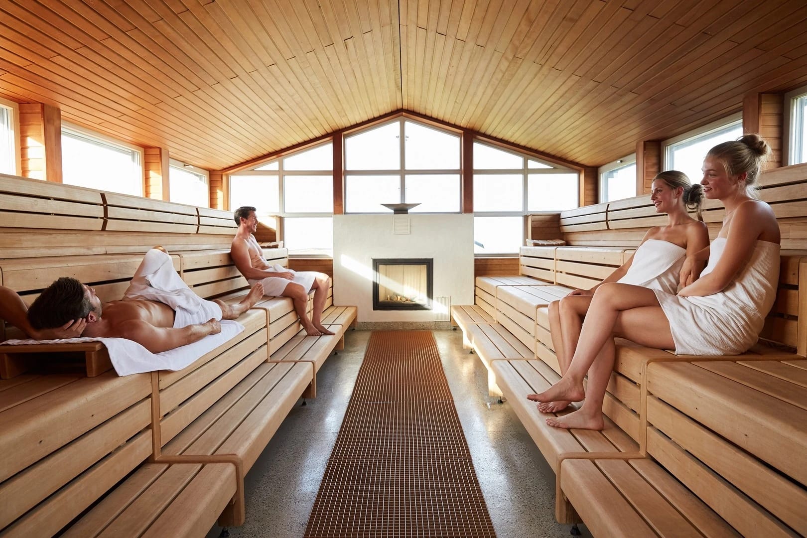 Sauna der benachbarten Dünen-Therme mit umlaufenden Sitzbänken, Panoramafenstern und Saunaofen