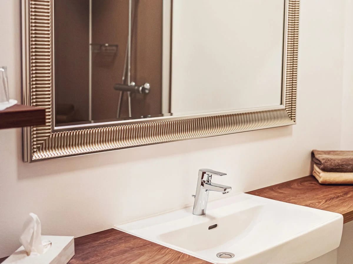 Badezimmer mit Waschbecken, gerahmtem Spiegel und Dusche