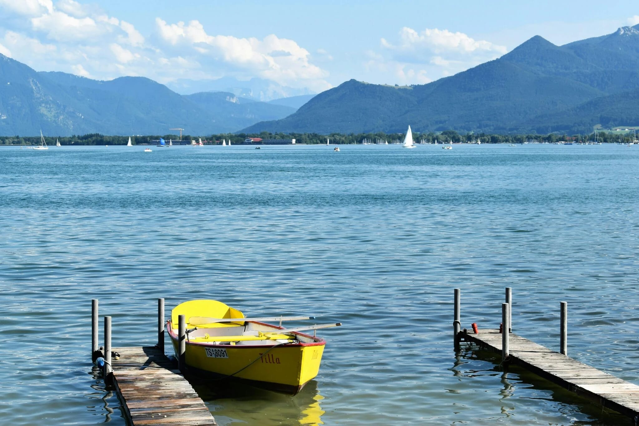 Chiemsee mit Steg, Ruderboot und Bergpanorama