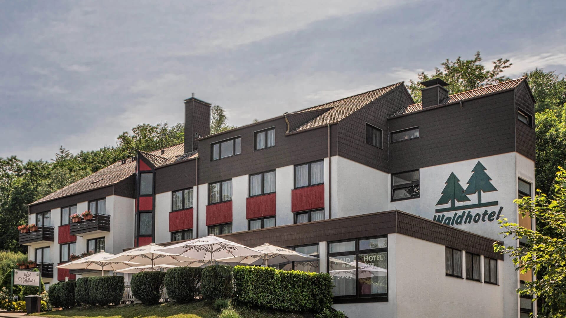 Hotelgebäude mit Terrasse und Sonnenschirmen davor