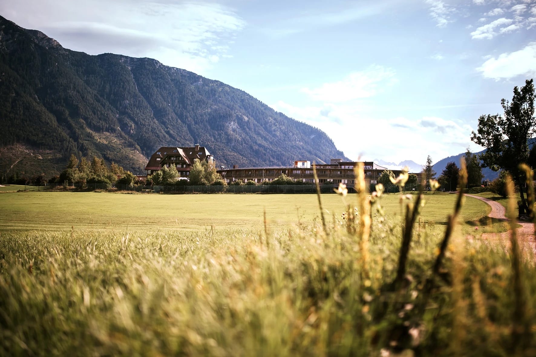 Hotelgebäude der Wasnerin in grüner Almlandschaft mit Bergen im Hintergrund