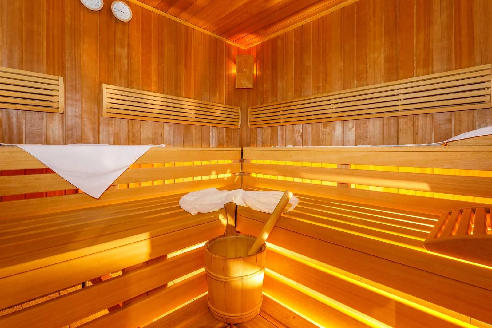 Warm beleuchtete finnische Sauna mit Holzbänken und Saunakübel