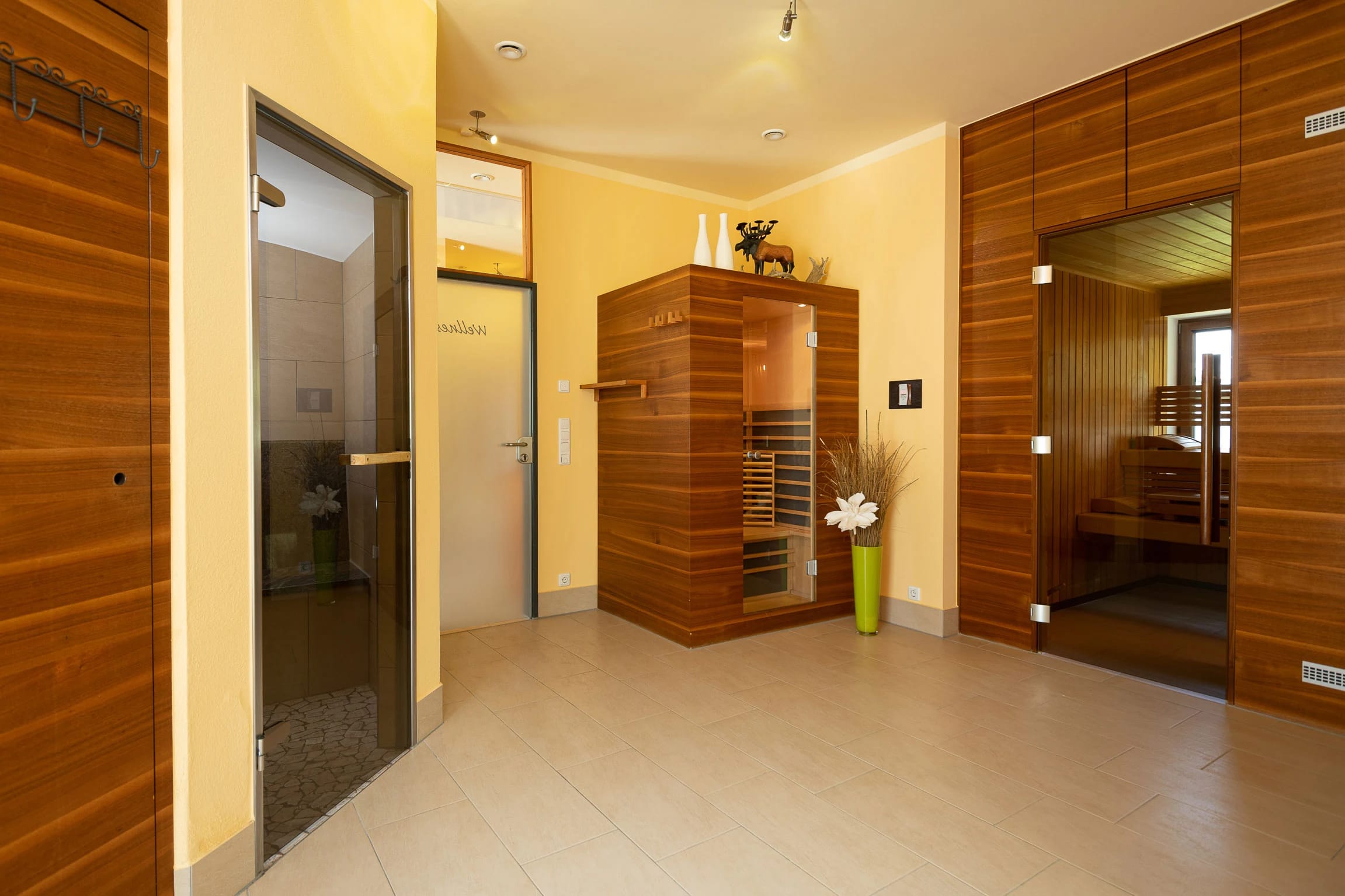 Saunabereich mit Infrarotkabine, holzverkleideter Sauna und Dusche im gefliesten Vorraum
